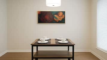 A dining area with a table, chairs, and a painting on the wall.