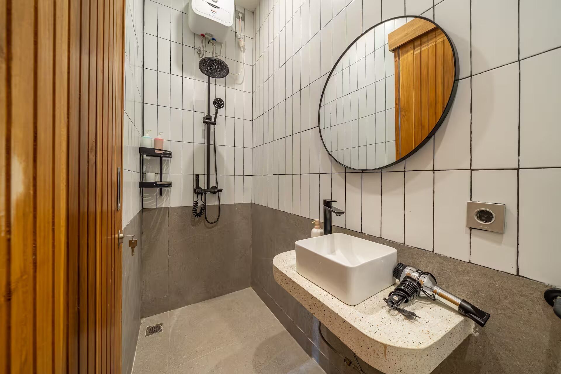 A bathroom with a shower, a sink, a mirror, and a wooden door.