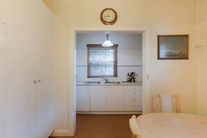 A compact kitchen with a sink, cabinets, and a clock above. - Stylish 1BR Vaucluse Escape | Near Shops & CBD (Vaucluse)