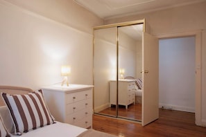 A bedroom with a bed, bedside table, lamp, and a mirrored wardrobe. - Stylish 1BR Vaucluse Escape | Near Shops & CBD (Vaucluse)