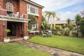 A two-story brick building with a balcony, a covered patio, and a well-maintained lawn. - Stylish 1BR Vaucluse Escape | Near Shops & CBD (Vaucluse)