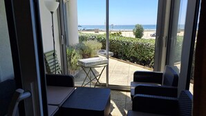 Ein Balkon mit Blick auf das Meer, einem Tisch und zwei Korbstühlen.