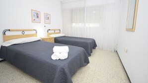 A room with two beds, a window with sheer curtains, and a mirror on the wall. - FLECHA (3 BEDROOMS) (Benidorm)