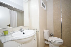 A bathroom with a white sink, mirror, toilet, and shower. - FLECHA (3 BEDROOMS) (Benidorm)