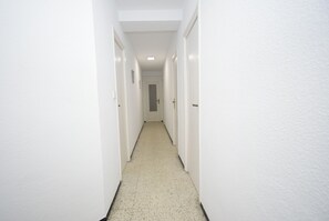 A narrow hallway with white walls and a speckled floor, leading to a door at the end. - FLECHA (3 BEDROOMS) (Benidorm)