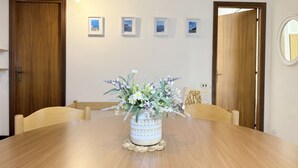 Une table à manger agrémentée d’un centre de table floral, de chaises en bois et de tableaux encadrés accrochés au mur.