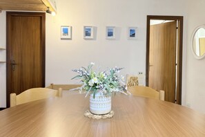 Ein Esstisch mit floraler Dekoration, Holzsessel und gerahmten Bildern an der Wand.