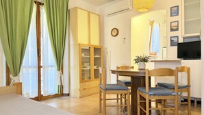 Une pièce comprenant une table à manger, des chaises, un buffet, un téléviseur et une horloge murale.