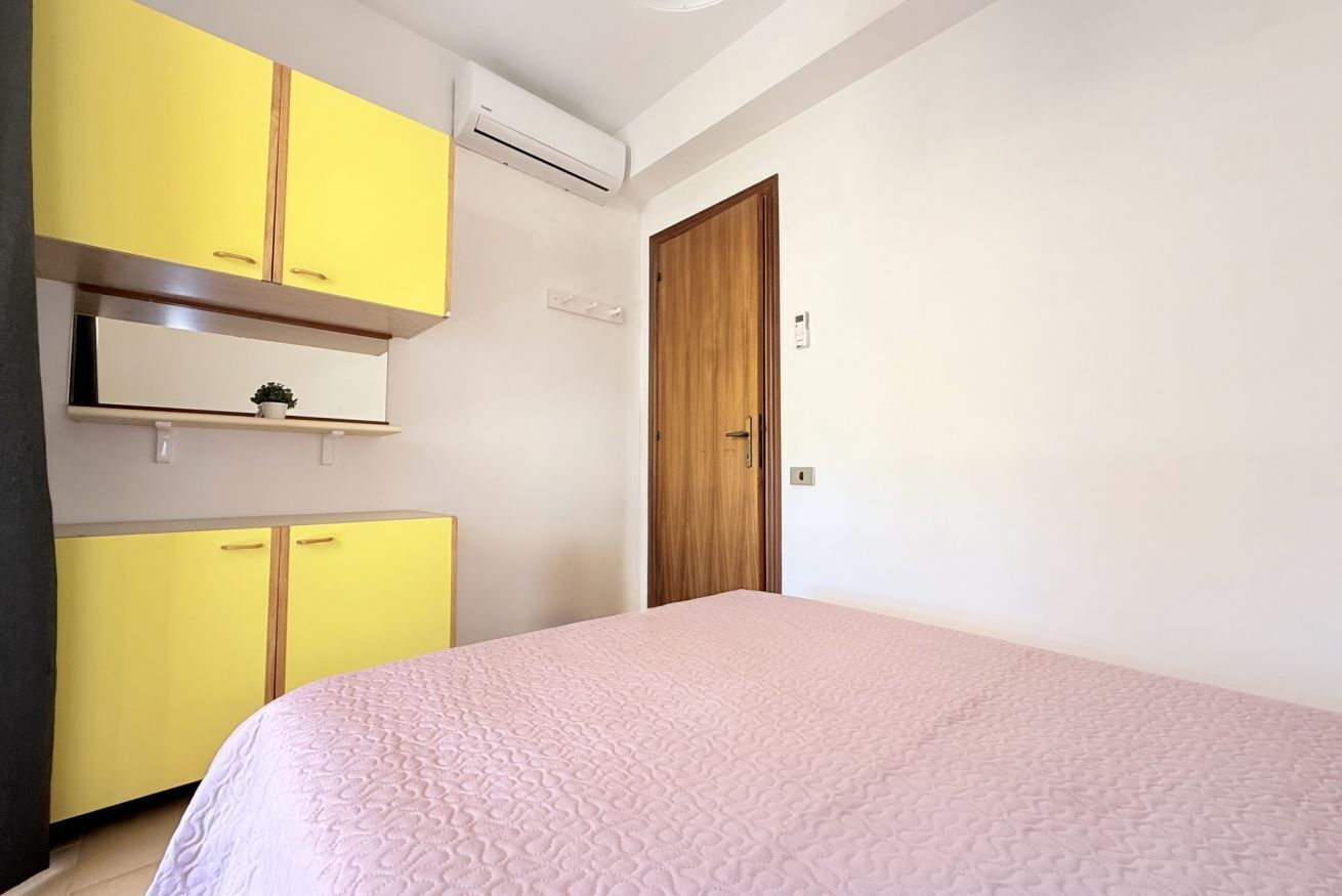 A bedroom with a bed, a wooden door, and yellow cabinets.