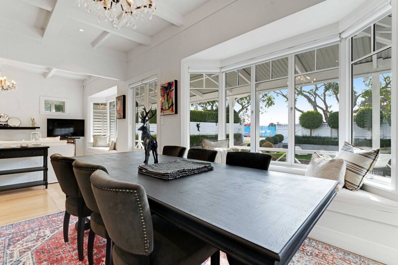 A spacious dining area with a large table, chairs, and a chandelier.