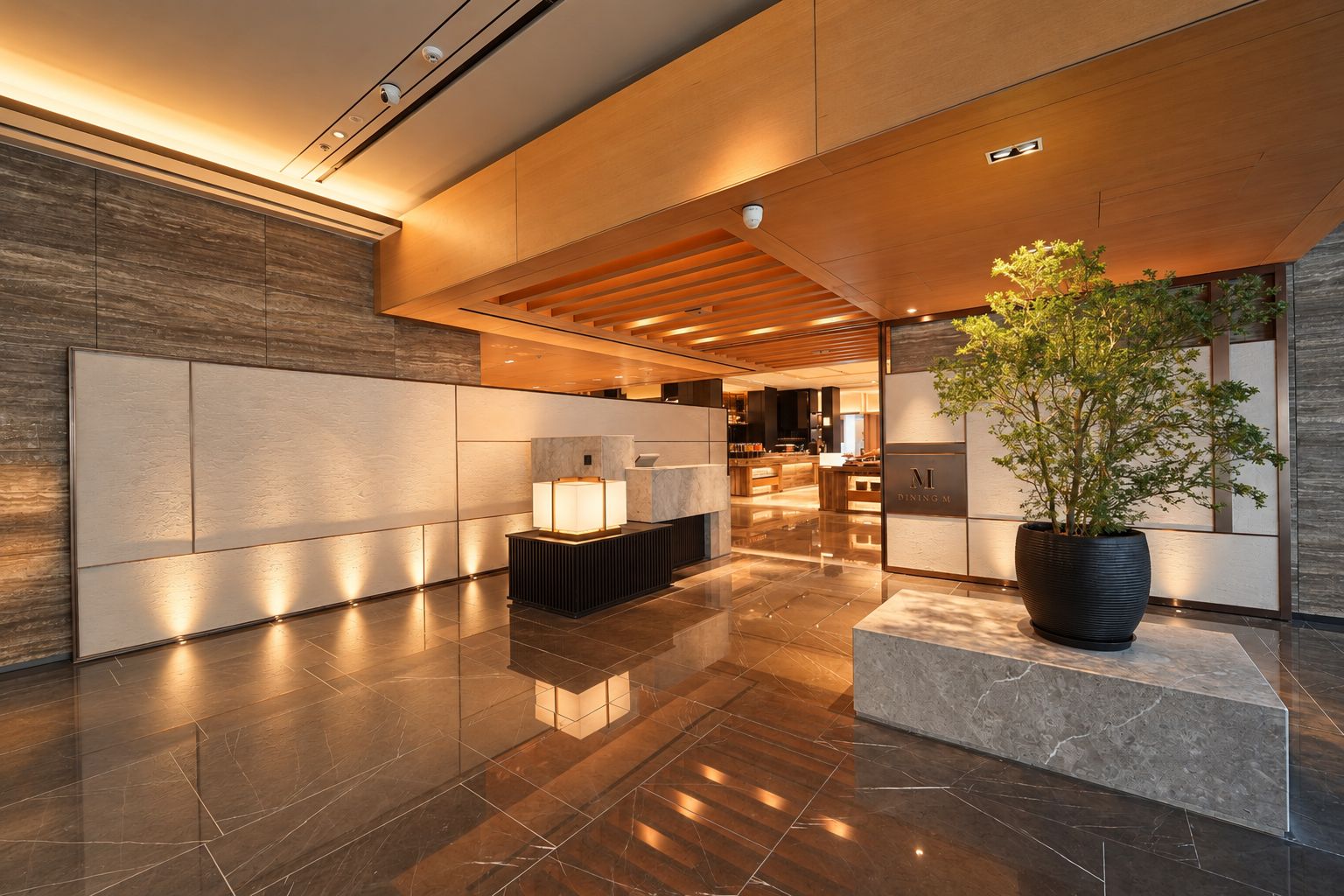 A modern lobby with a reception desk, a large potted plant, and a polished marble floor.