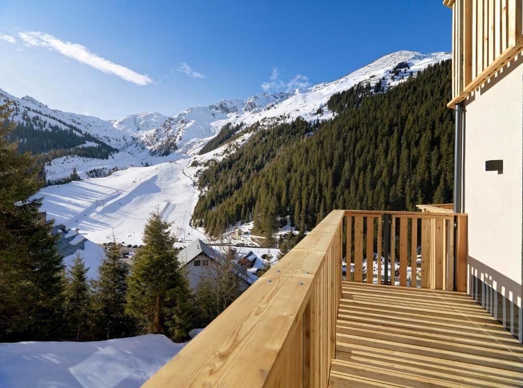Een houten terras met uitzicht op een besneeuwd berglandschap.