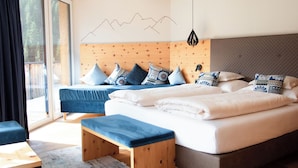 Een moderne slaapkamer met een groot bed, twee kleinere bedden, een bankje en uitzicht op de omgeving.