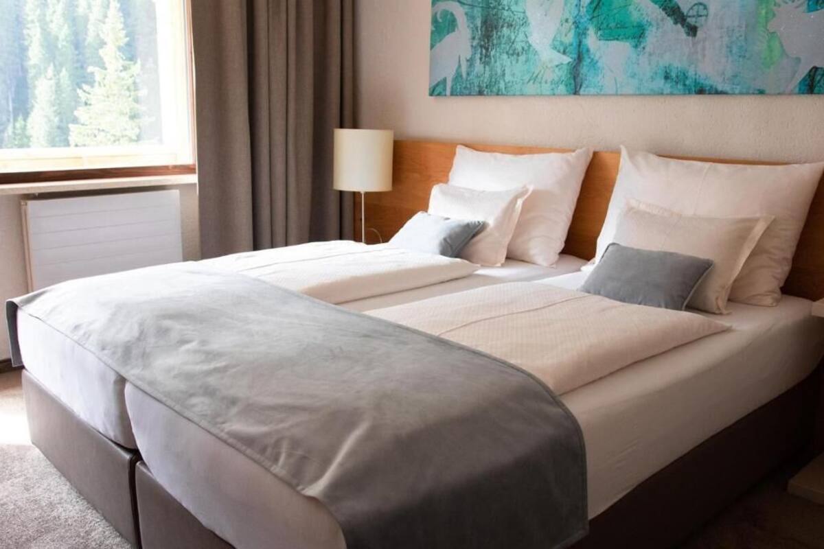 Una cama doble con cabecera, una lámpara de noche y un cuadro en la pared.