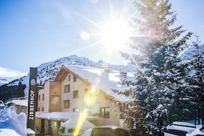 A building with a sign reading 'ZIRBENHOF' in a snowy landscape with mountains in the background. - Hotel Zirbenhof (Hochfügen)