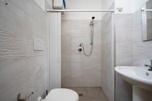 Un baño con ducha, inodoro, lavamanos y espejo.