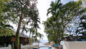 Ein Swimmingpool, umgeben von Palmen, mit Blick auf das Meer.