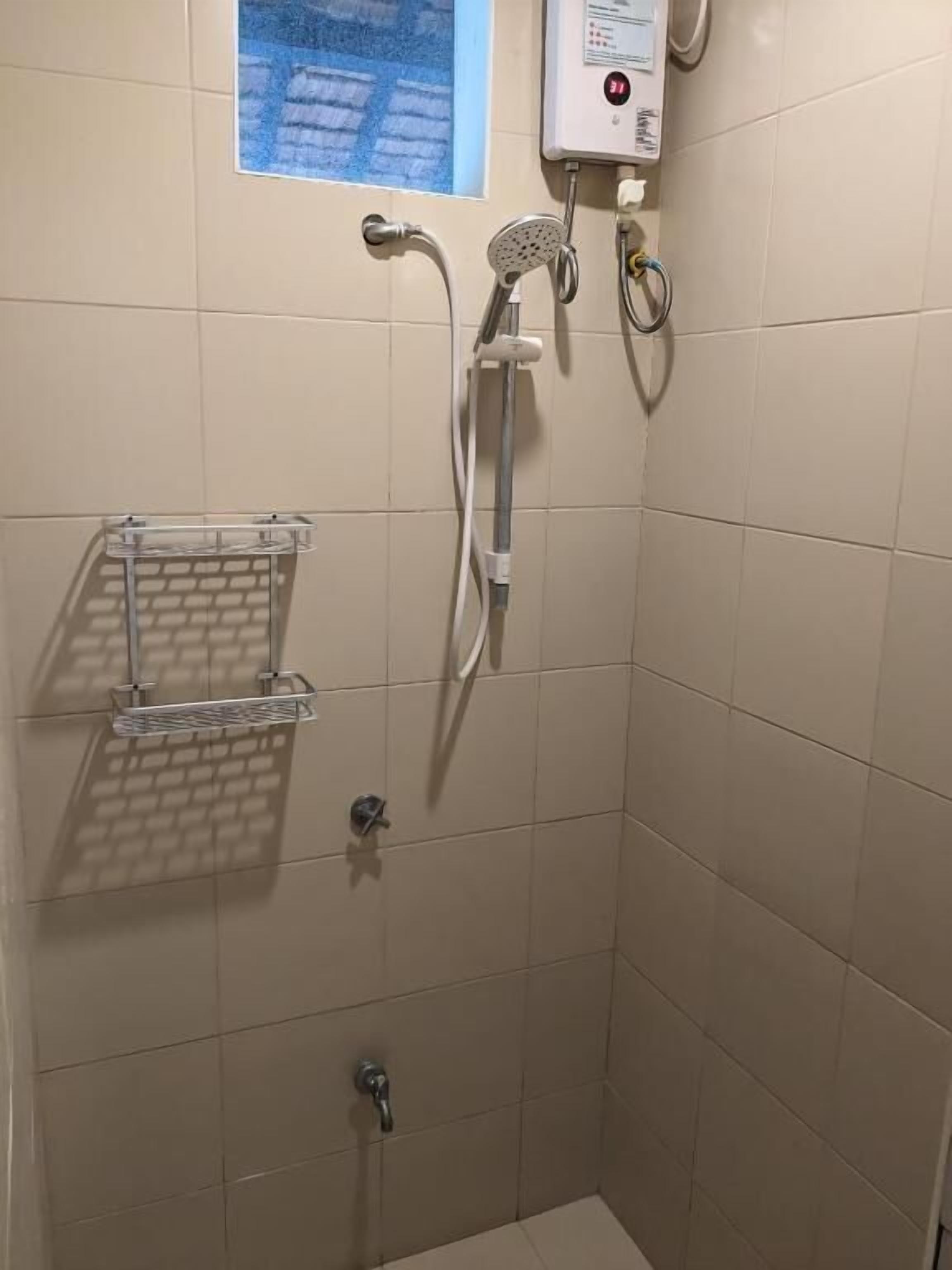 A shower with a handheld showerhead, a wall-mounted faucet, and a control panel.