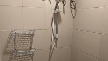 A shower with a handheld showerhead, a wall-mounted faucet, and a control panel.