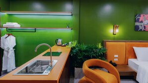 A modern hotel room with a sink, a bed, a chair, and a green wall. - Bee Stay Apartment Huy Van (Hanoi)