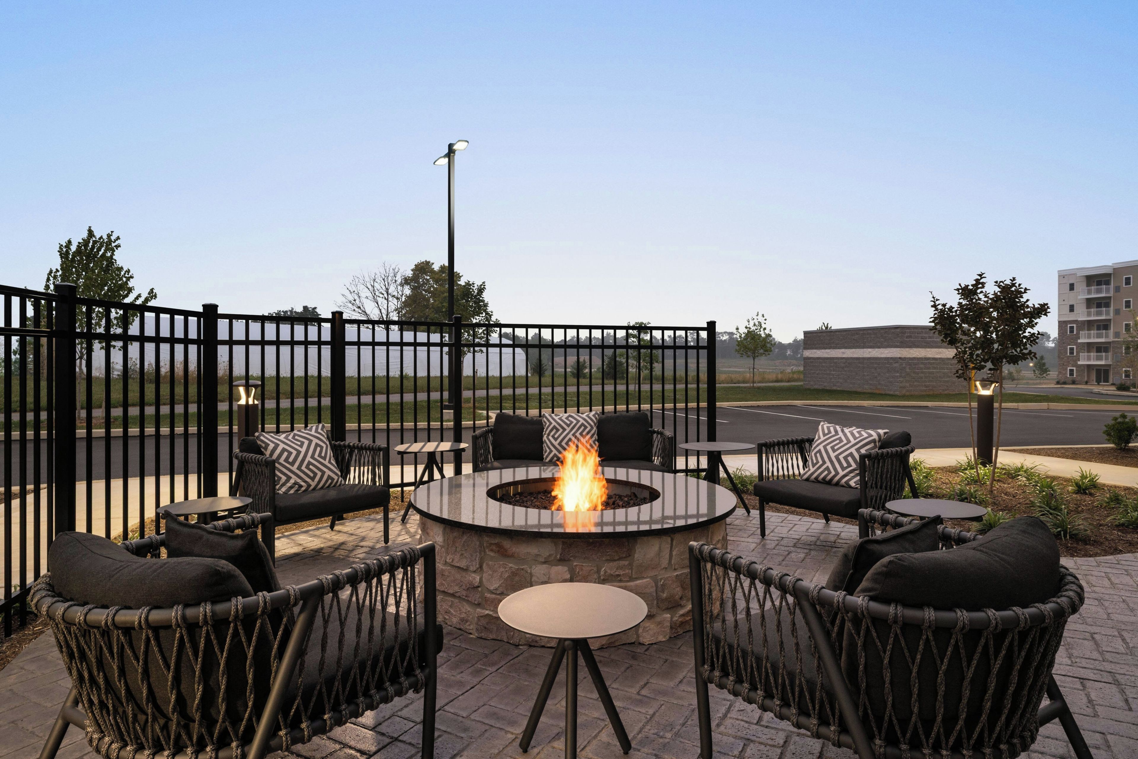 An outdoor seating area with a fire pit, surrounded by wicker furniture and a stone fire table.