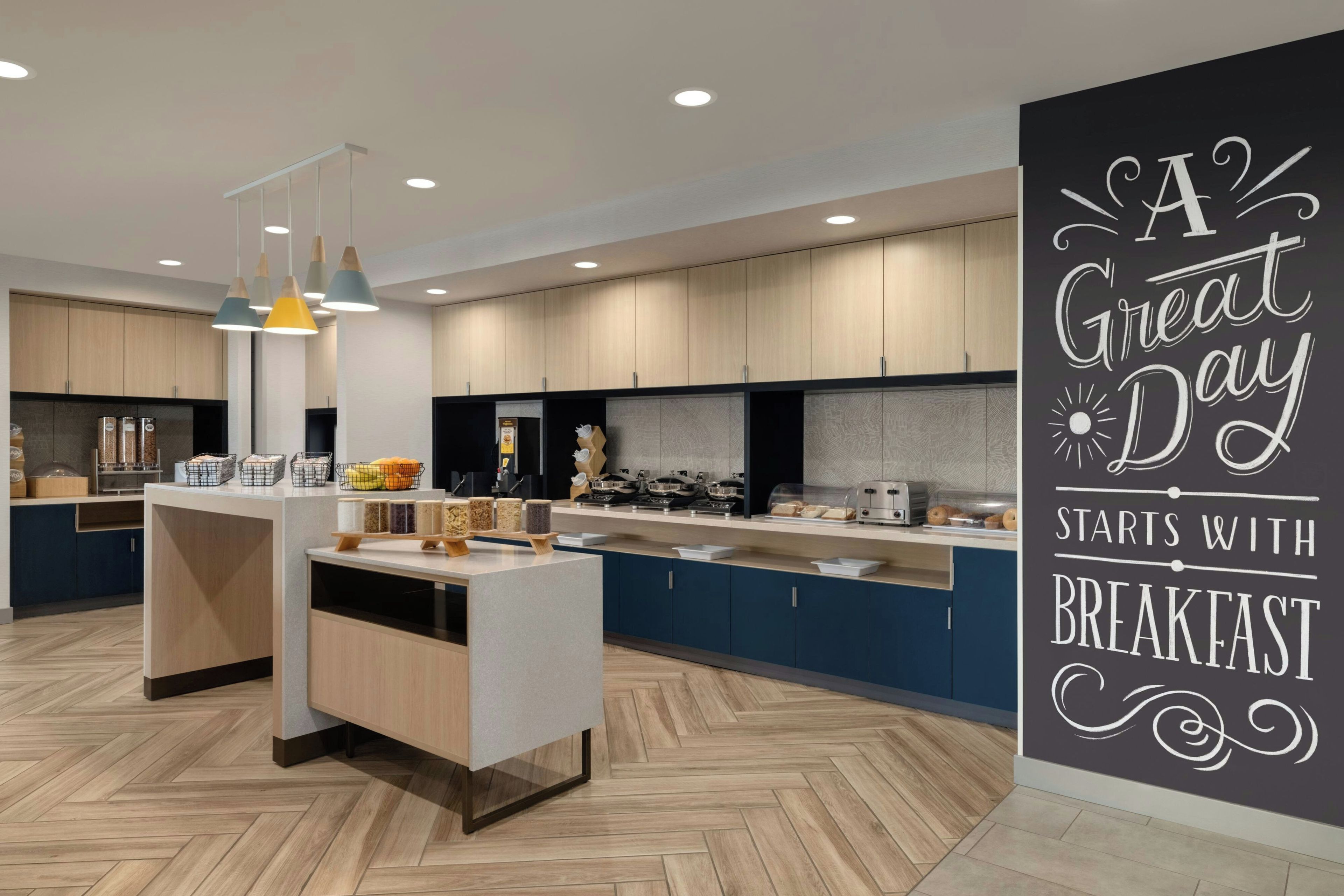 Una cocina moderna con una isla central, iluminación colgante y una barra de desayuno.