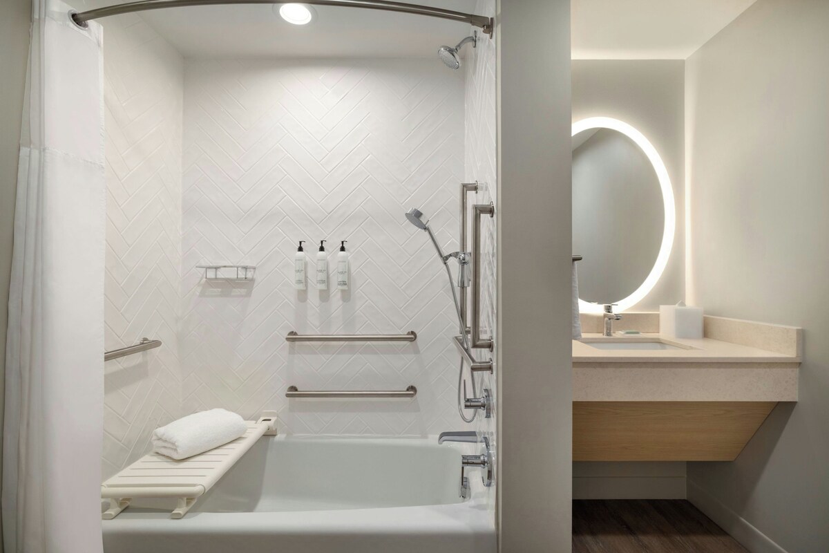 A modern bathroom with a walk-in shower, a bathtub, a vanity with a mirror, and a towel rack.