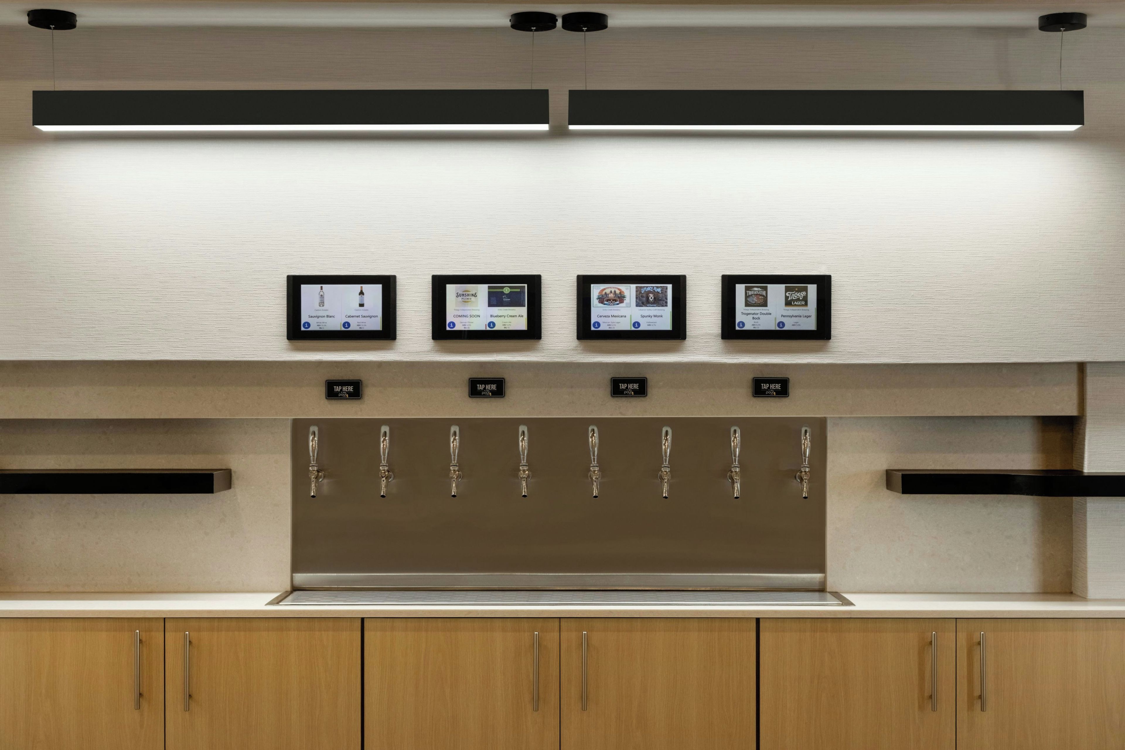 A modern kitchen with a built-in wine cooler displaying various wines.