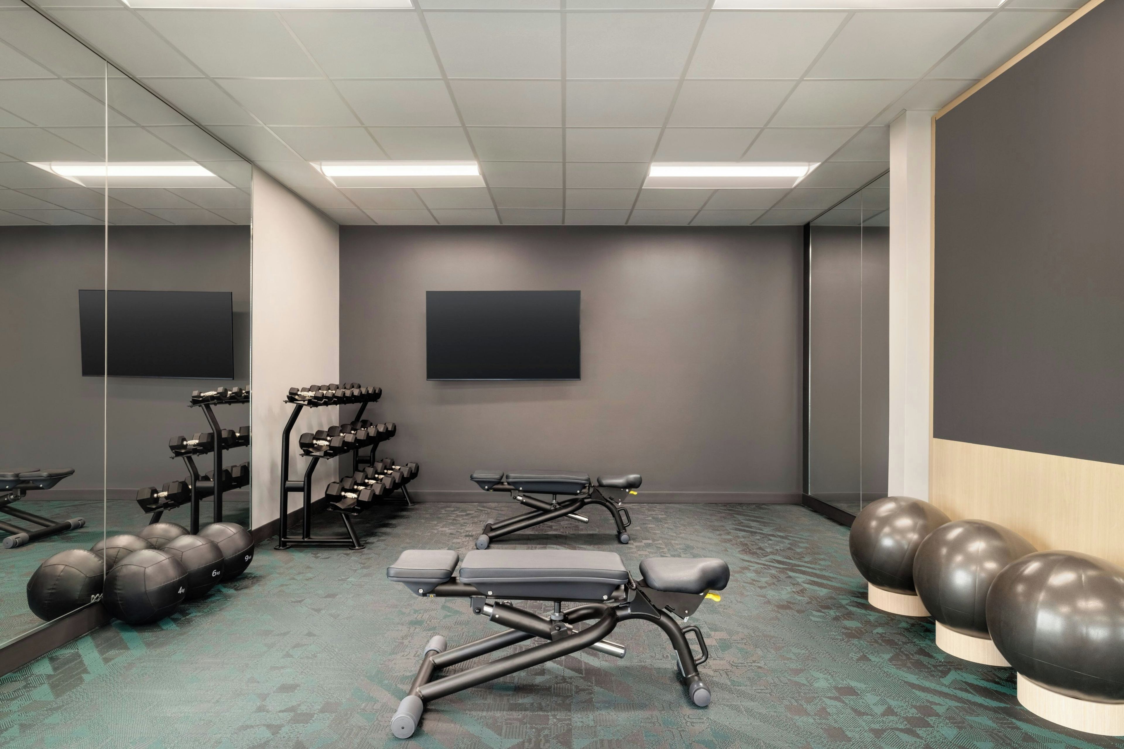 Un gimnasio con equipo de ejercicio, espejos y una alfombra estampada.