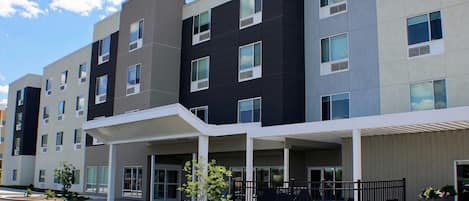 A multi-story residential building with a covered entrance, multiple windows, and a gated outdoor area.