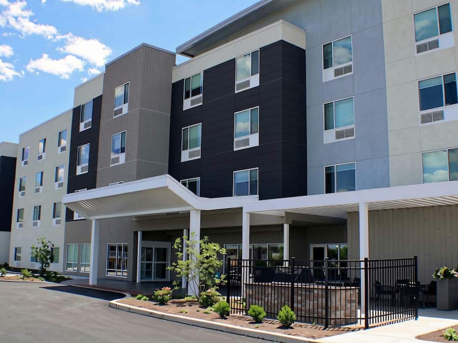 A multi-story residential building with a covered entrance, multiple windows, and a gated outdoor area.