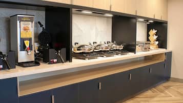 Eine moderne Küche mit Kaffeemaschine, einem Waffeleisen und mehreren Induktionskochfeldern.