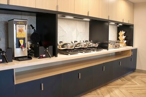Una cocina moderna con cafetera, plancha para gofres y varias placas de cocción por inducción.