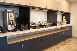 Una cocina moderna con cafetera, plancha para gofres y varias placas de cocción por inducción.