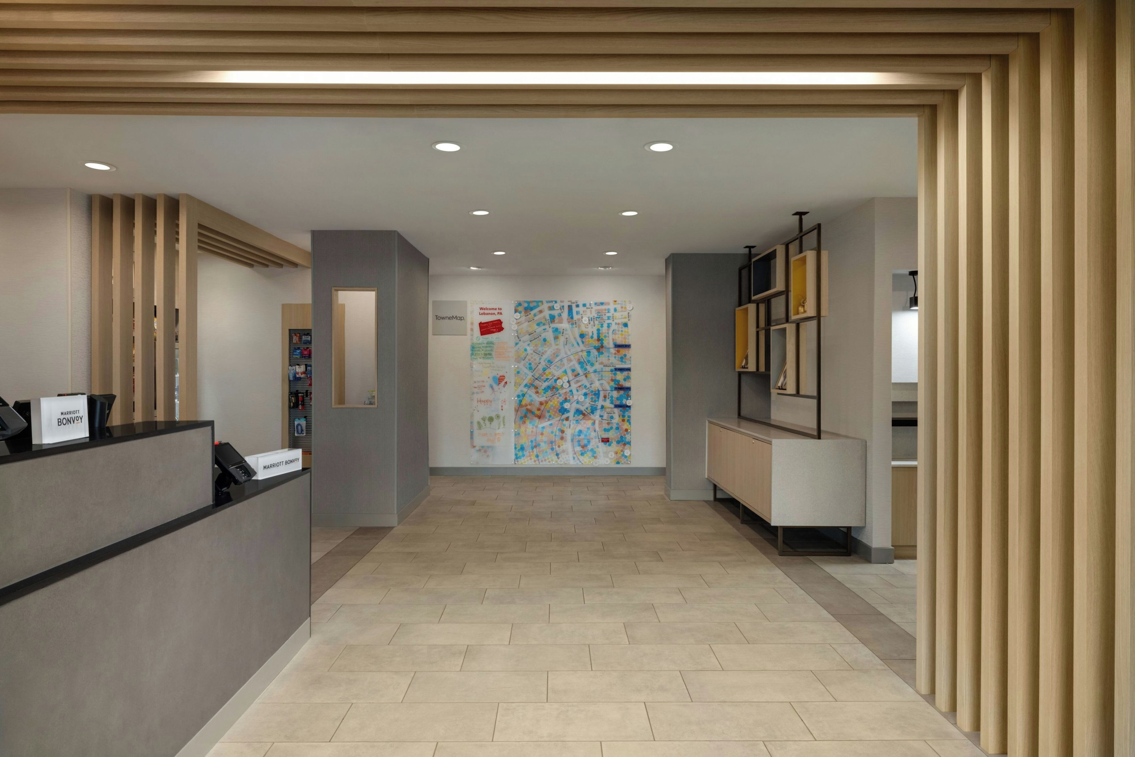 Een hotel receptie met een receptiebalie, een kaart aan de muur en een gang naar andere kamers.