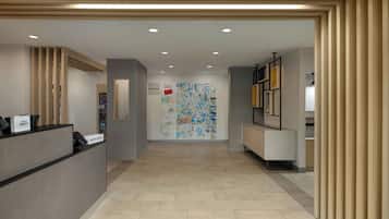 A hotel reception area with a reception desk, a map on the wall, and a corridor leading to other rooms.