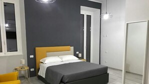 Een moderne slaapkamer met een bed, een klein nachtkastje, een stoel en een kledingkast.