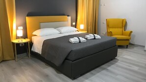 A modern hotel room with a bed, bedside lamps, a chair, and a neatly made bed with towels.