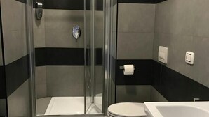 A modern bathroom with a glass-enclosed shower, a toilet, and a bathtub.