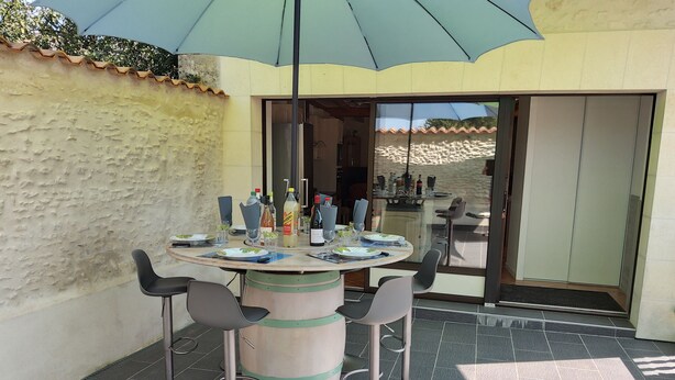 A round table with chairs, a bar area, and a view through a glass door. - Between river and town center - air-conditioned - 2 WCs - enclosed courtyard (Cognac)
