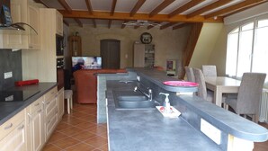 A kitchen with a long counter, a built-in oven, and a television. - Between river and town center - air-conditioned - 2 WCs - enclosed courtyard (Cognac)