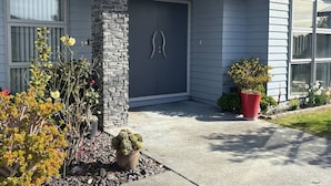 A residential house with a stone pillar, a dark front door, and a potted plant in the front yard. - Modern Napier Comfort (Napier)