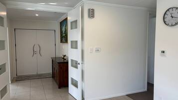 Un pasillo con una puerta blanca, un reloj y un armario pequeño.