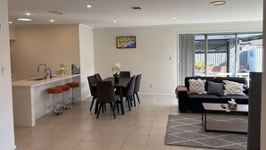 A modern living room with a black sofa, a coffee table, and a dining area with a table and chairs. - Modern Napier Comfort (Napier)