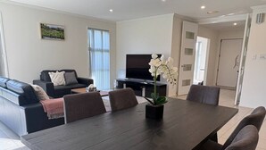 A modern living room with a dark wooden dining table, a sofa, and a television. - Modern Napier Comfort (Napier)