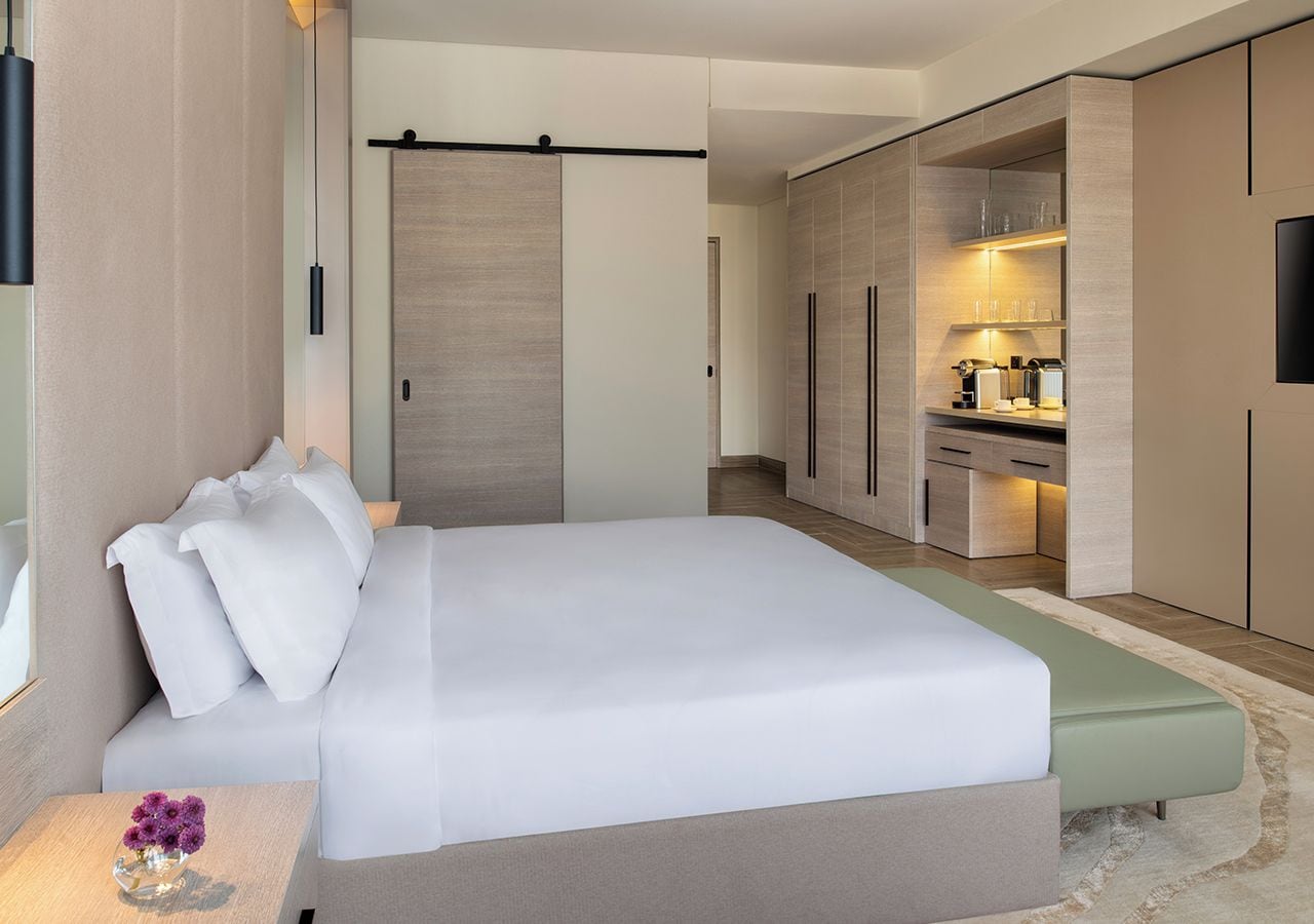 Una habitación de hotel moderna con una cama grande, una mesita de noche, un escritorio y un armario.
