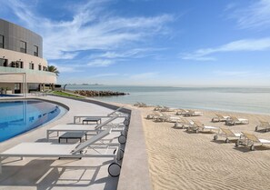 A pool area with lounge chairs and a building with a curved facade. - Ray Hotel by Cloud 7 (Mangaf)