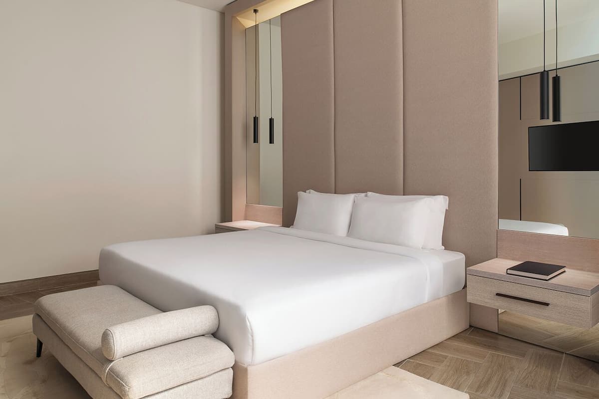 Un dormitorio moderno con una cama grande, mesitas de noche y un espejo.