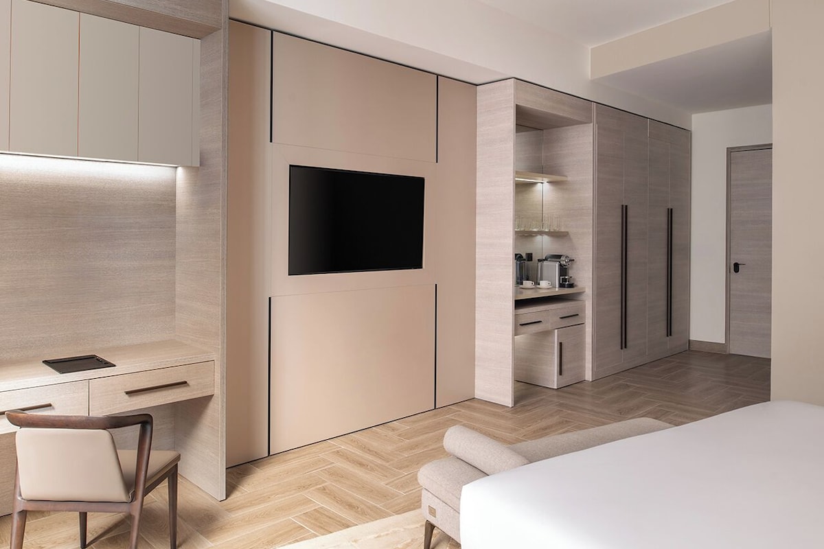 Un dormitorio moderno con una cama, un escritorio y una televisión.