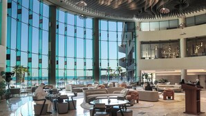 A spacious lobby with seating areas, a podium, and large windows offering views of the outside. - Ray Hotel by Cloud 7 (Mangaf)